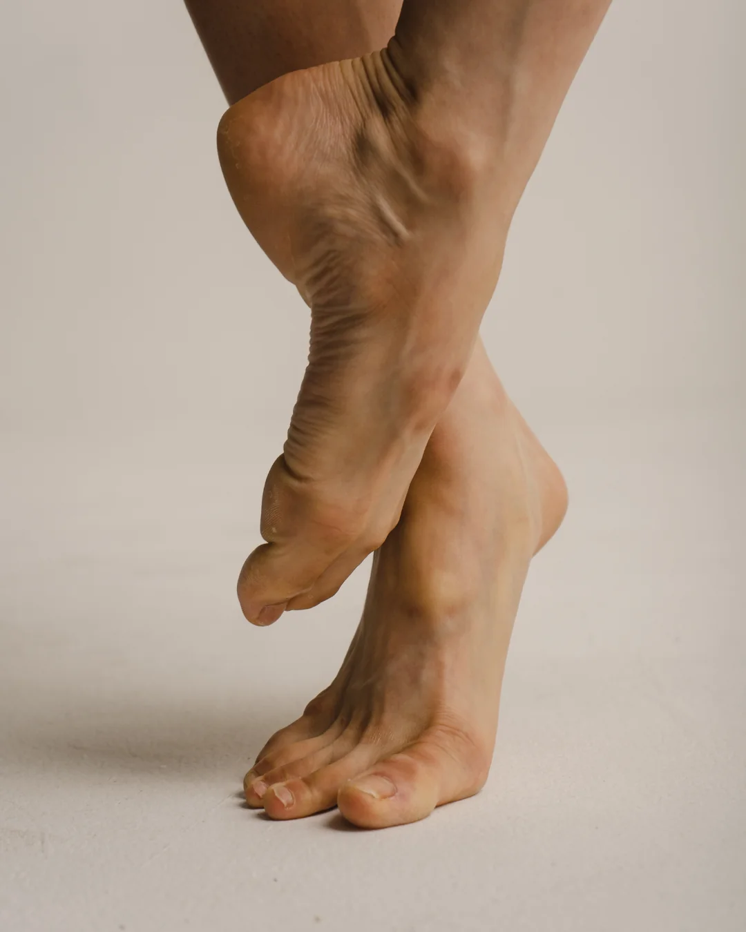 Pieds de ballerine en relevé, étude photographique sur fond sable