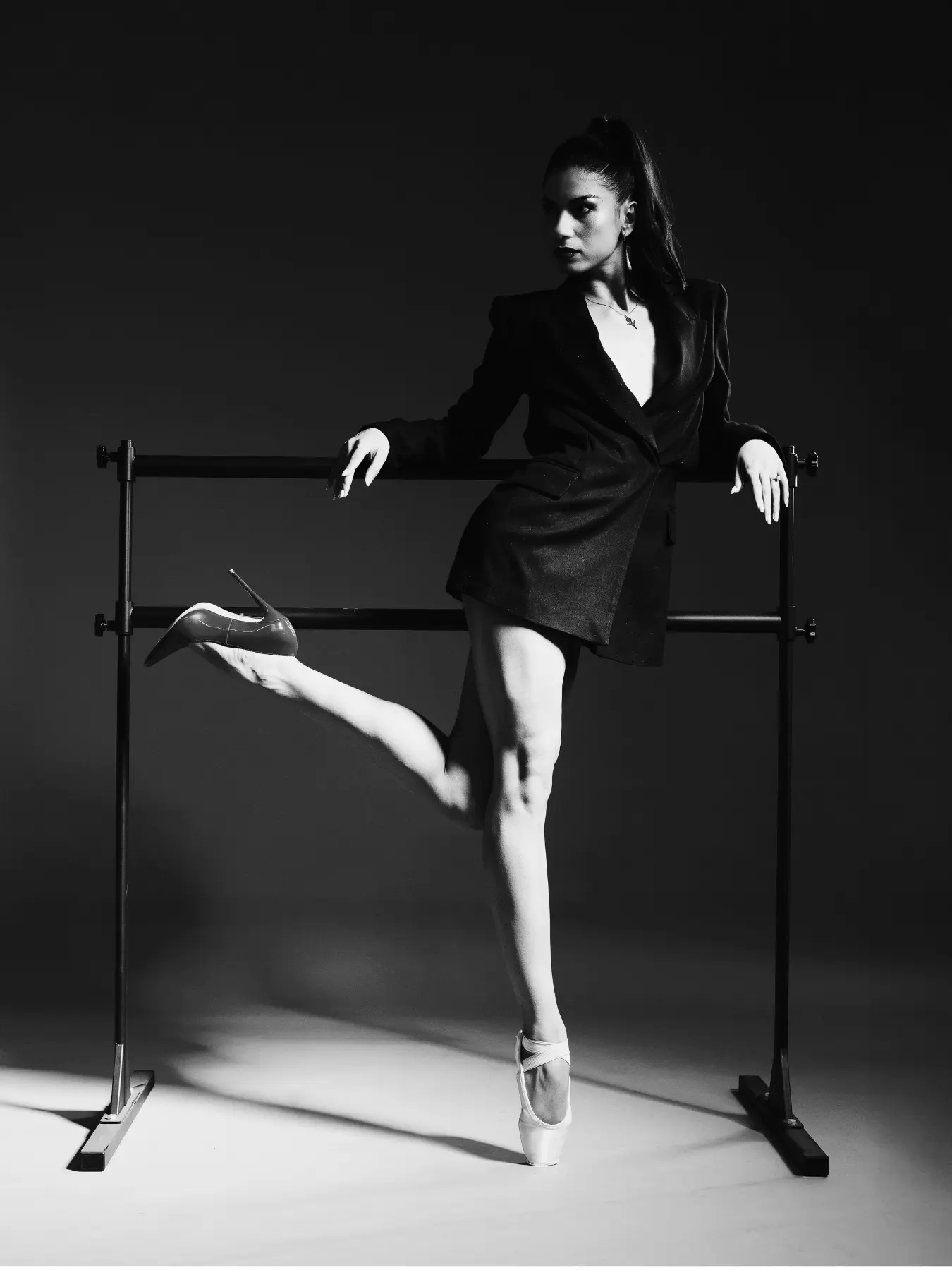 Danseuse en blazer à la barre, talon aiguille tendu, noir et blanc