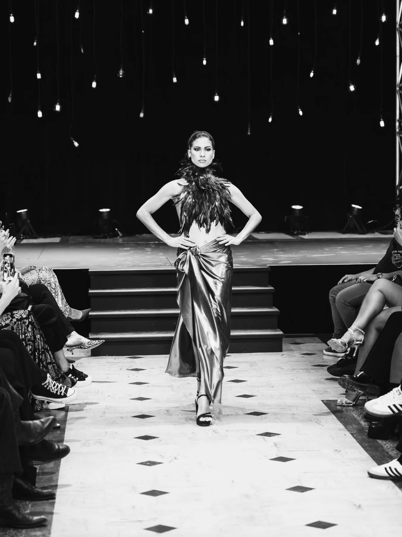 Défilé de mode : plumes noires et jupe métallisée devant le public, noir et blanc