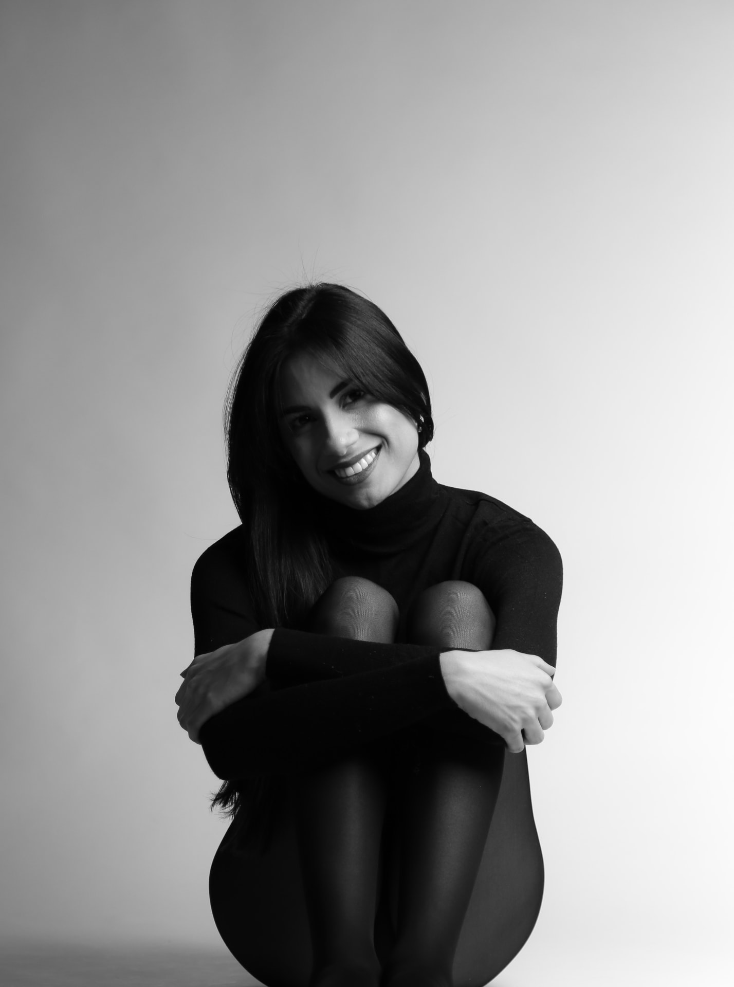 Portrait souriant de Claudia Cristina en col roulé noir, noir et blanc
