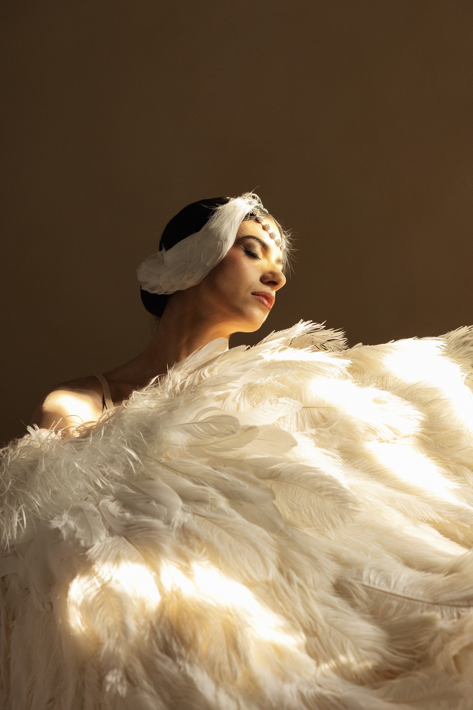 Claudia Cristina en coiffe de plumes blanches, portrait lumineux