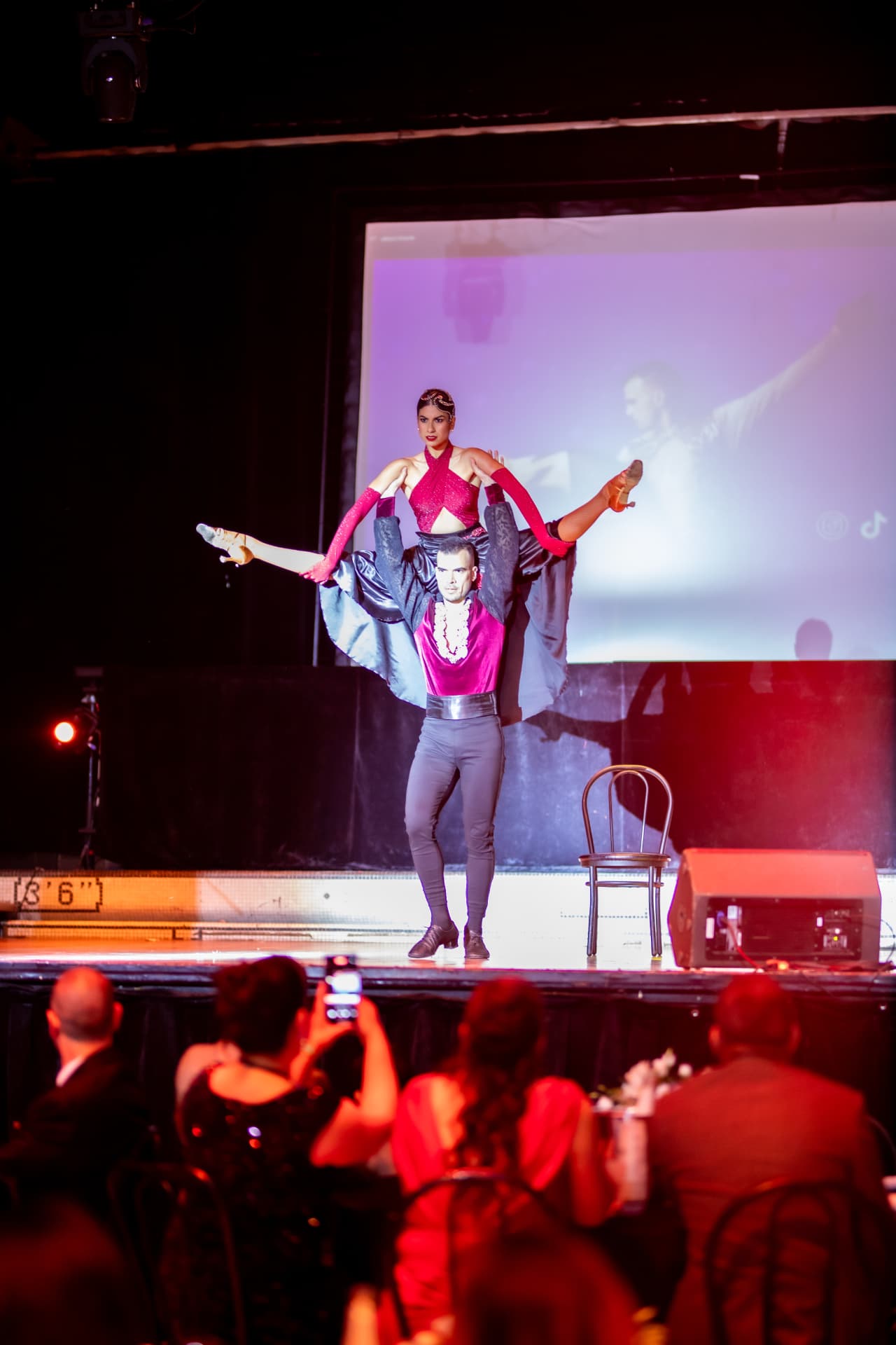 Porté acrobatique d'un duo de danseurs en costume rose sur scène lors d'un gala