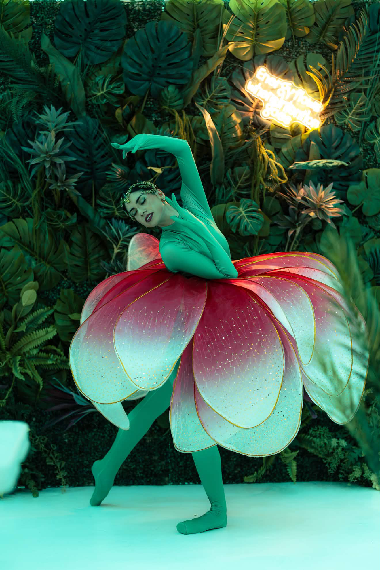 Danseuse en costume de fleur devant un mur végétal, événement gastronomique