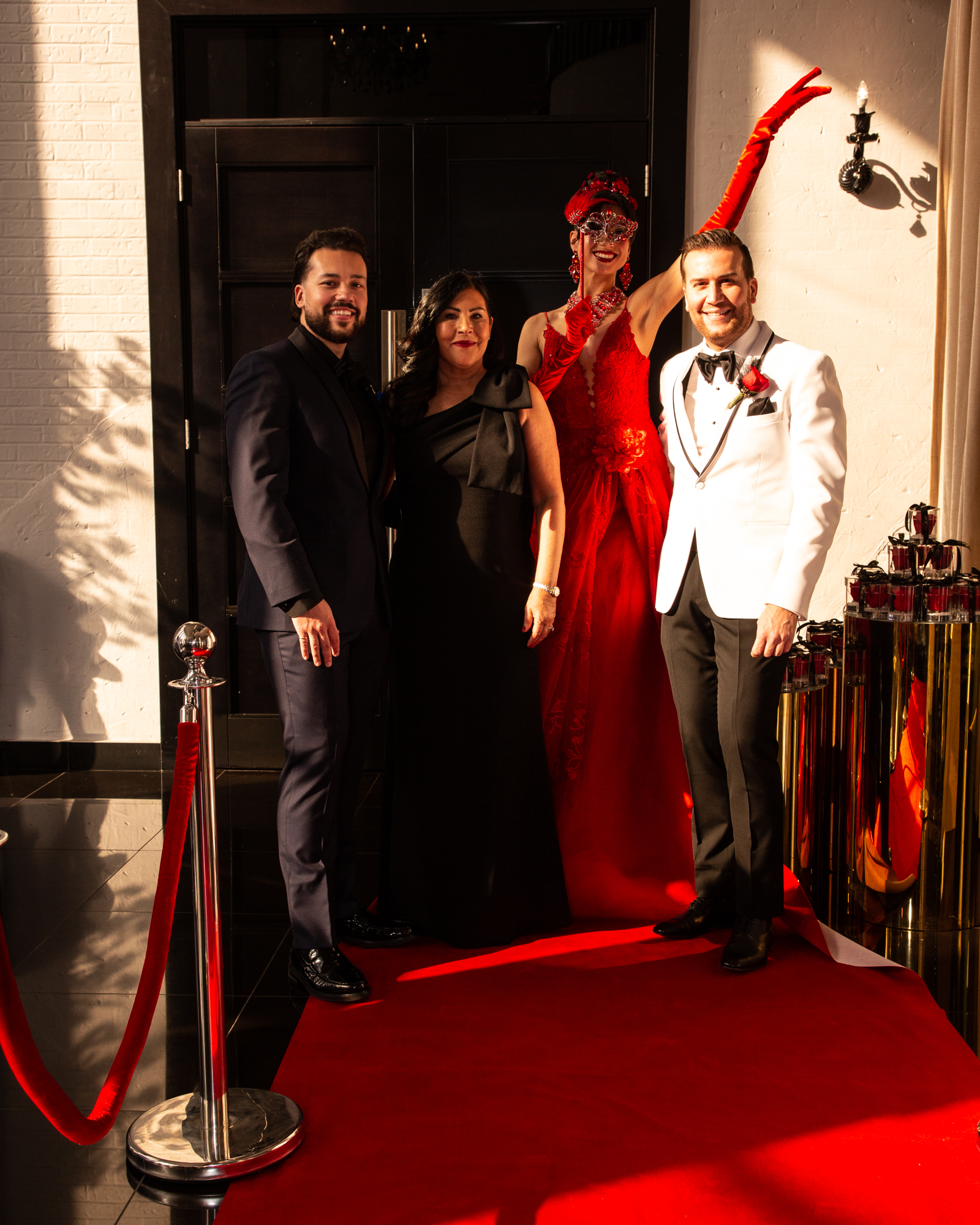 Hôtesse en robe rouge posant avec les invités sur le tapis rouge