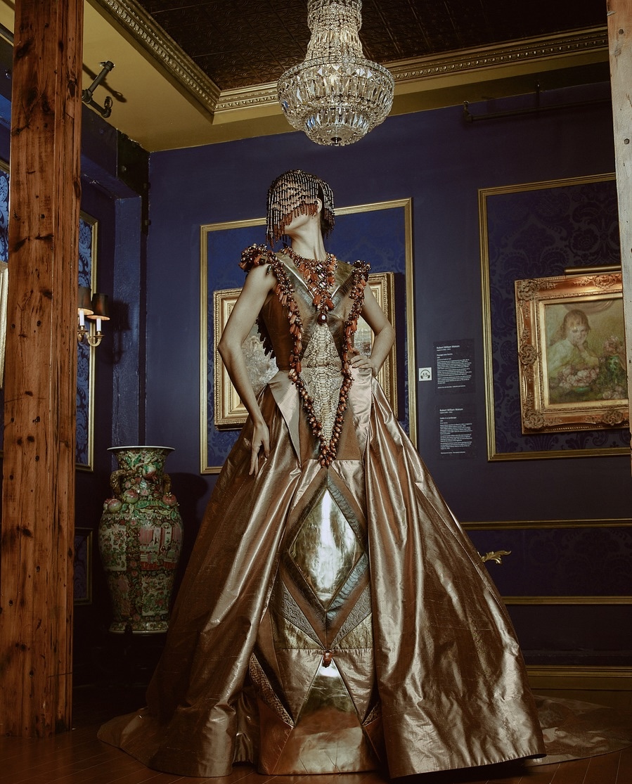 Robe sculpturale dorée dans un salon patrimonial aux murs bleu nuit