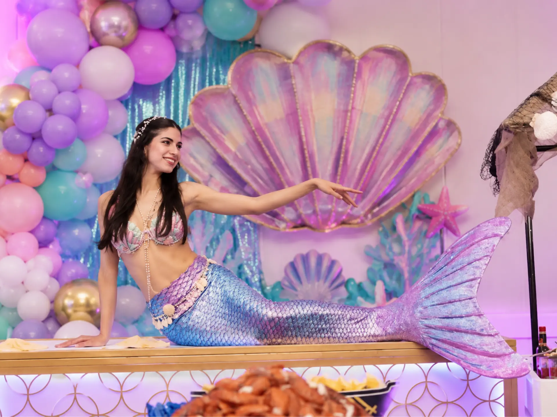 Performeuse sirène dans un décor de coquillage lors d'une fête d'enfants