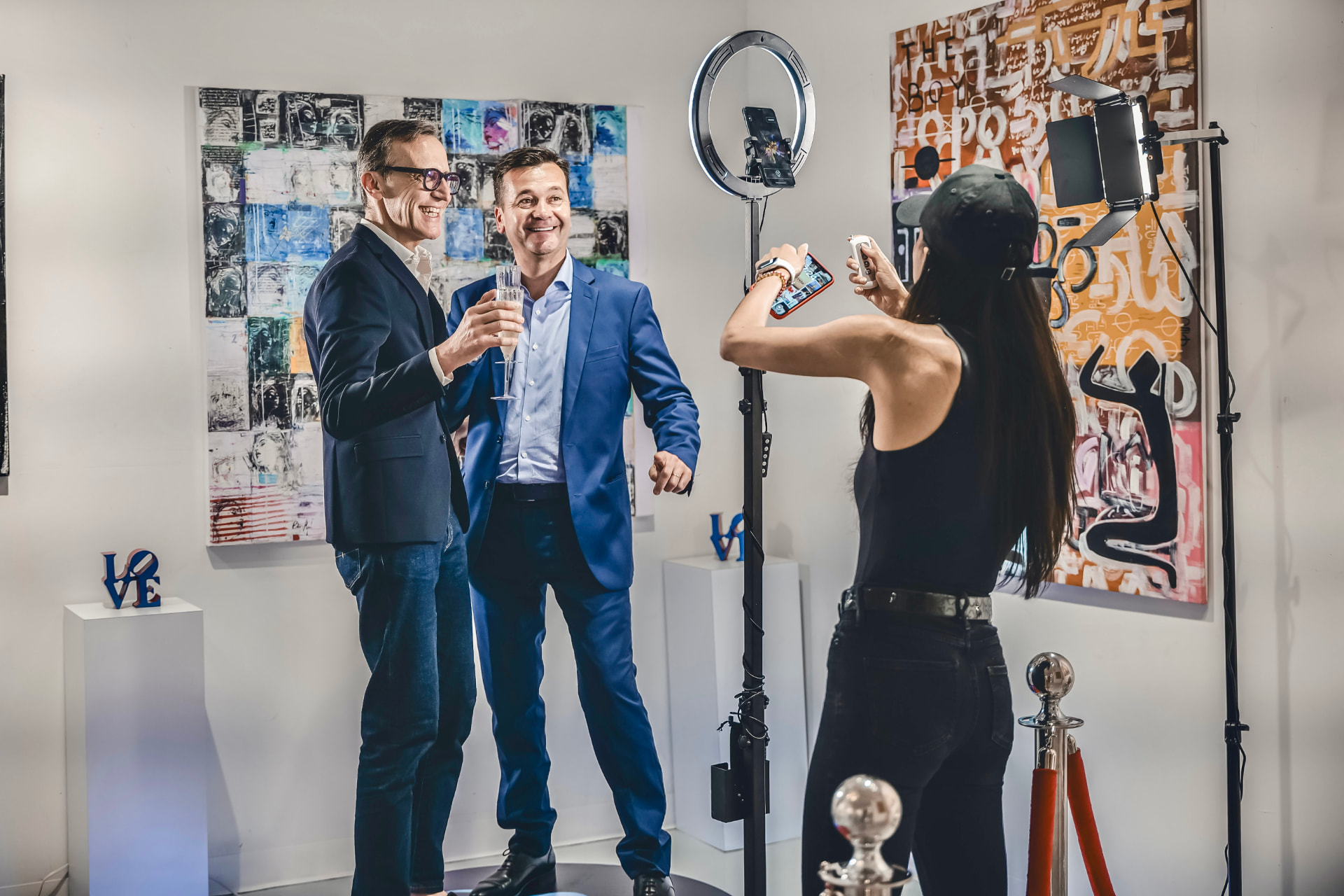 Invités en costume trinquant devant une cabine vidéo 360 lors d'une soirée privée