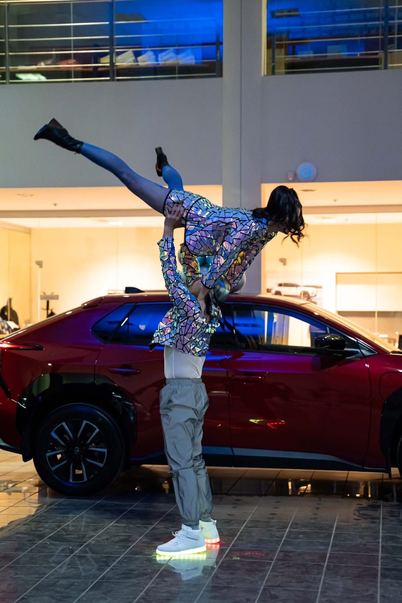 Porté acrobatique en costumes miroir devant une voiture rouge en showroom