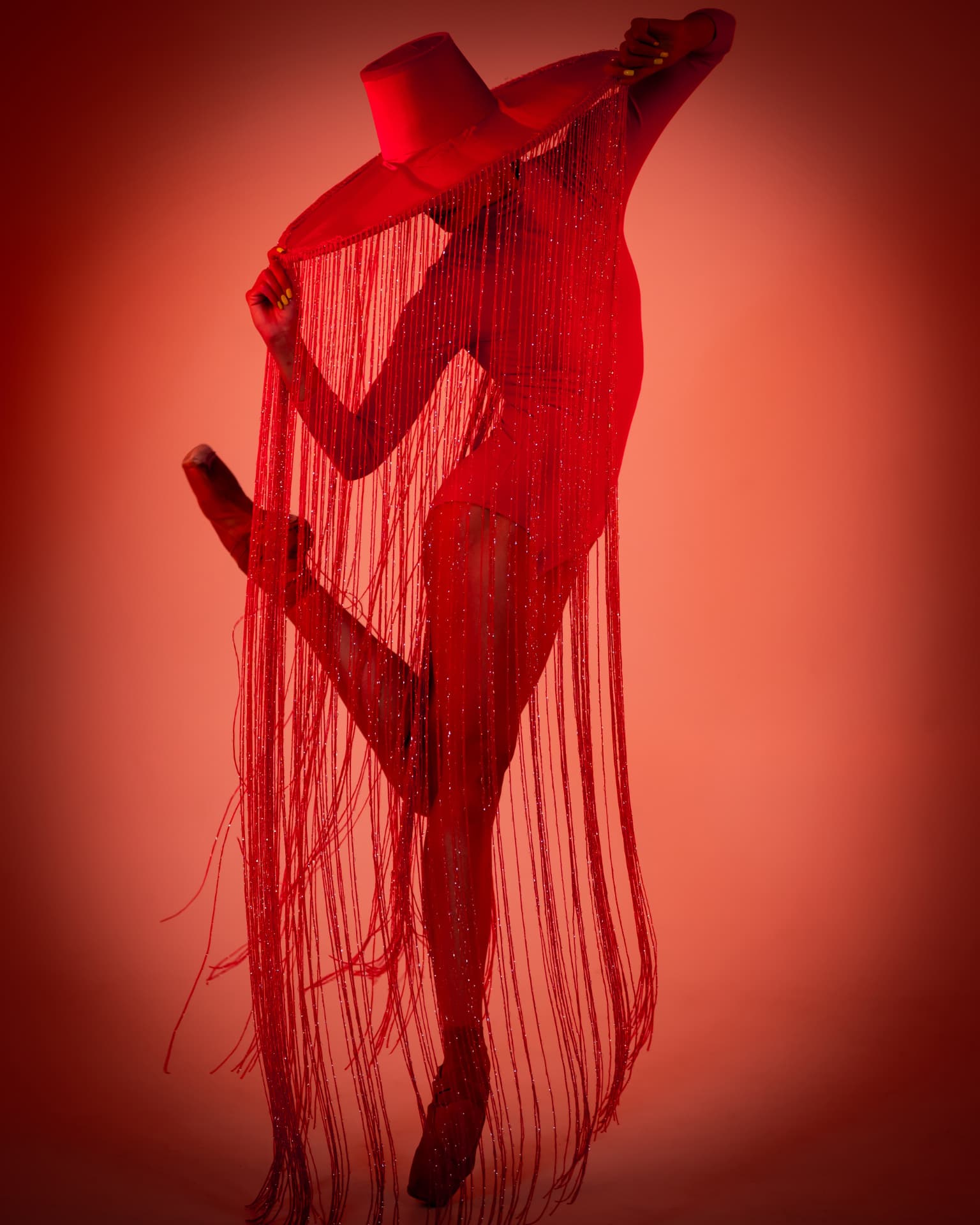 Danseuse en costume à franges rouges scintillantes sous une lumière écarlate